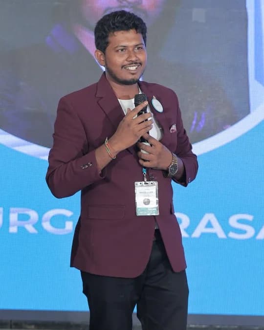 Dr. Yamarthi Sai Durga Prasad speaking on stage with a microphone
